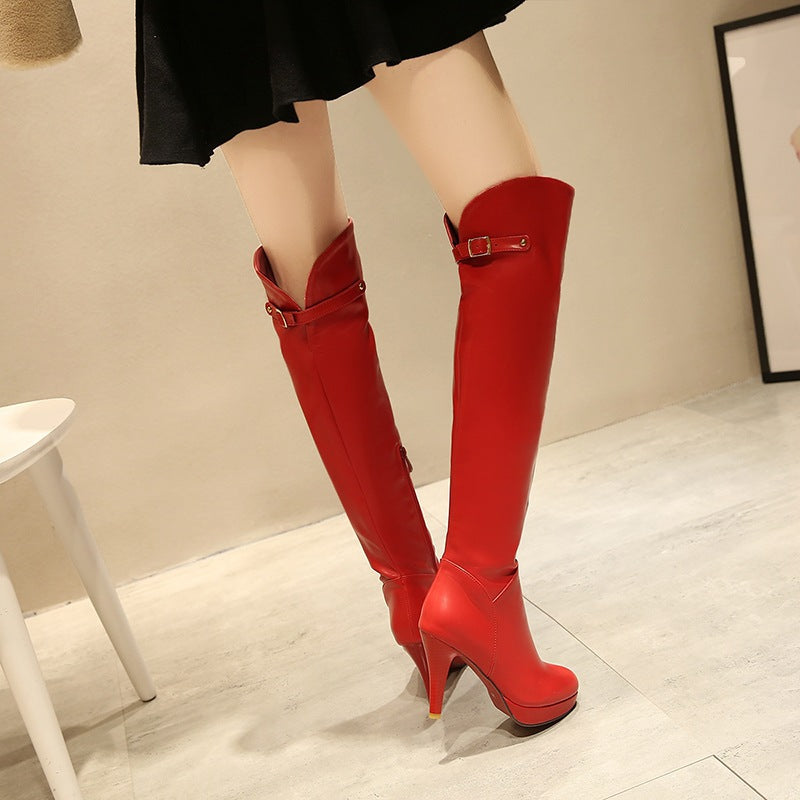 Red knee-high boots worn with a black skirt on a light wooden floor.