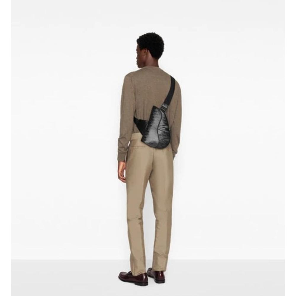 Person wearing a beige outfit with a black bag on a white background