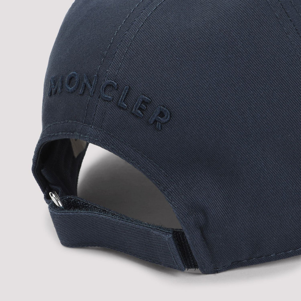 Navy blue cap with 'Moncler' branding on a light gray background