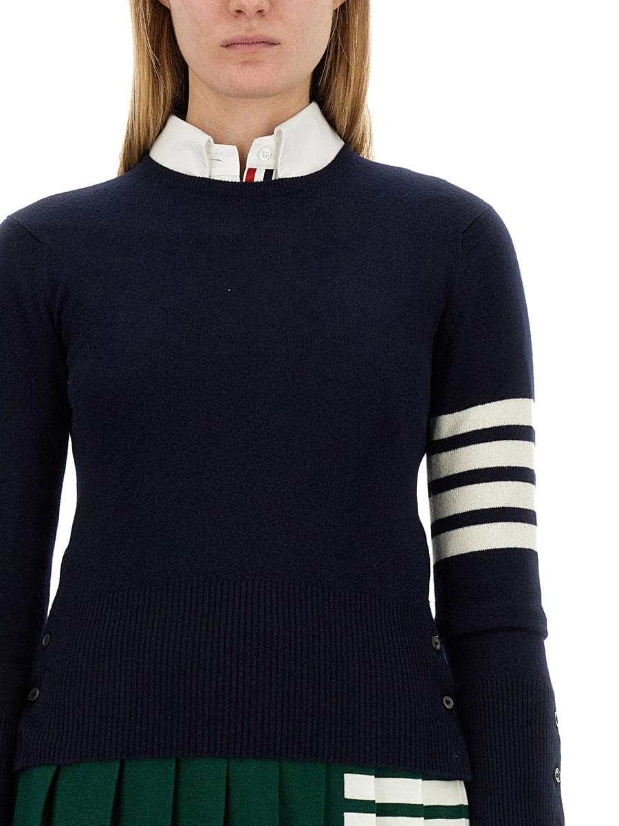 Navy sweater with white stripes on sleeves worn by a person