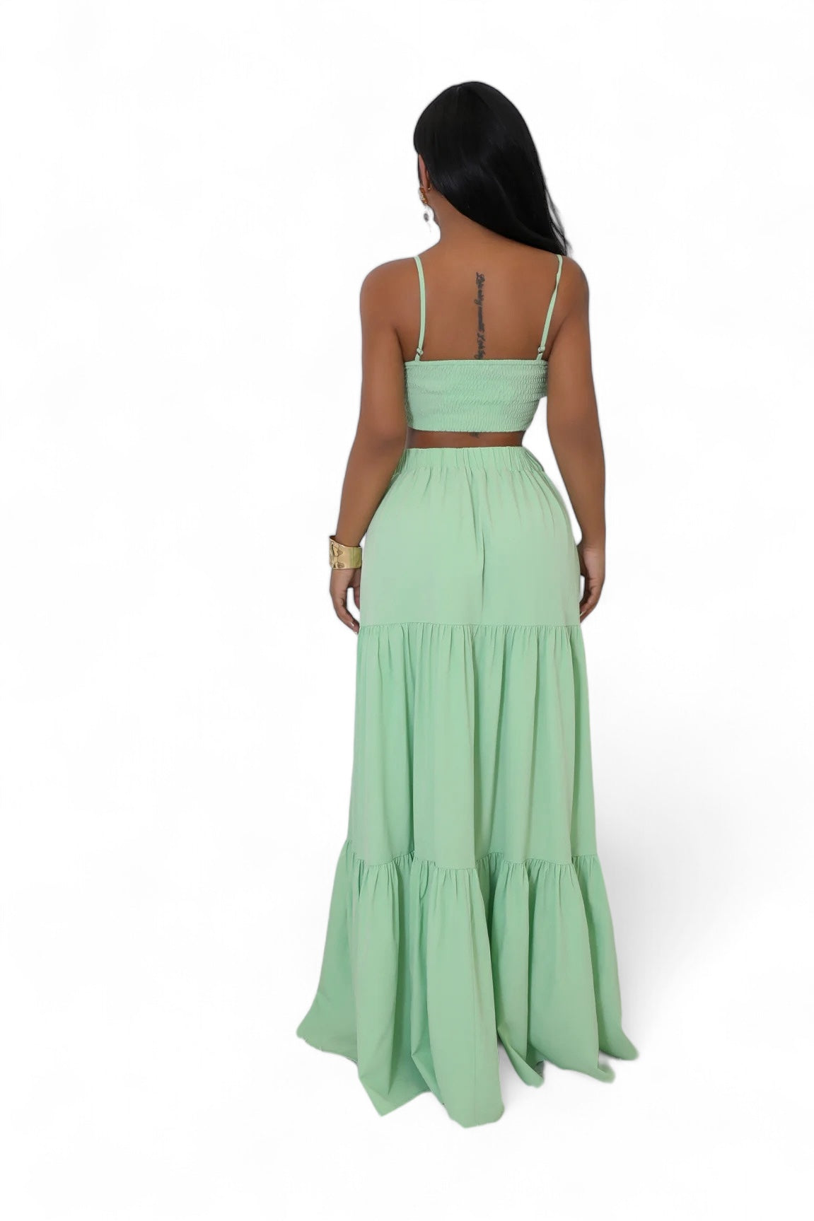 Woman wearing a light green two-piece dress with a white background