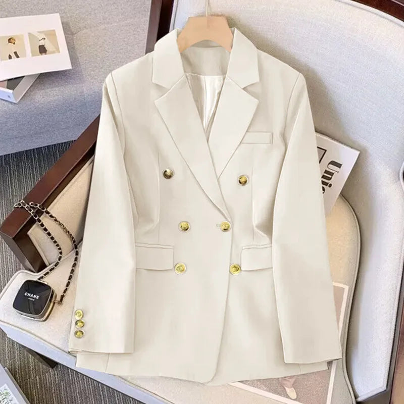 Beige blazer with gold buttons on a hanger against a neutral background