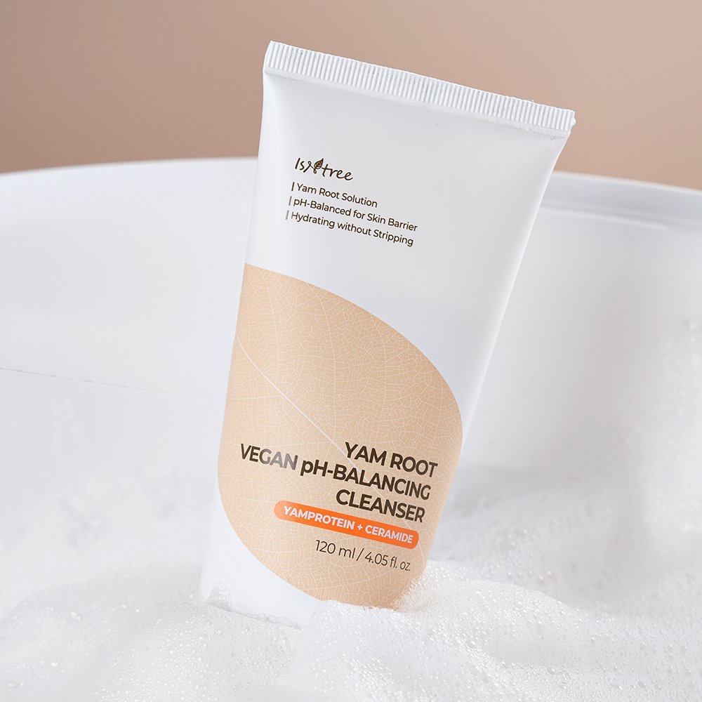 A squeeze tube of isyree Yam Root Vegan pH-Balancing Cleanser standing upright in white bath foam, with a soft beige and white label design.