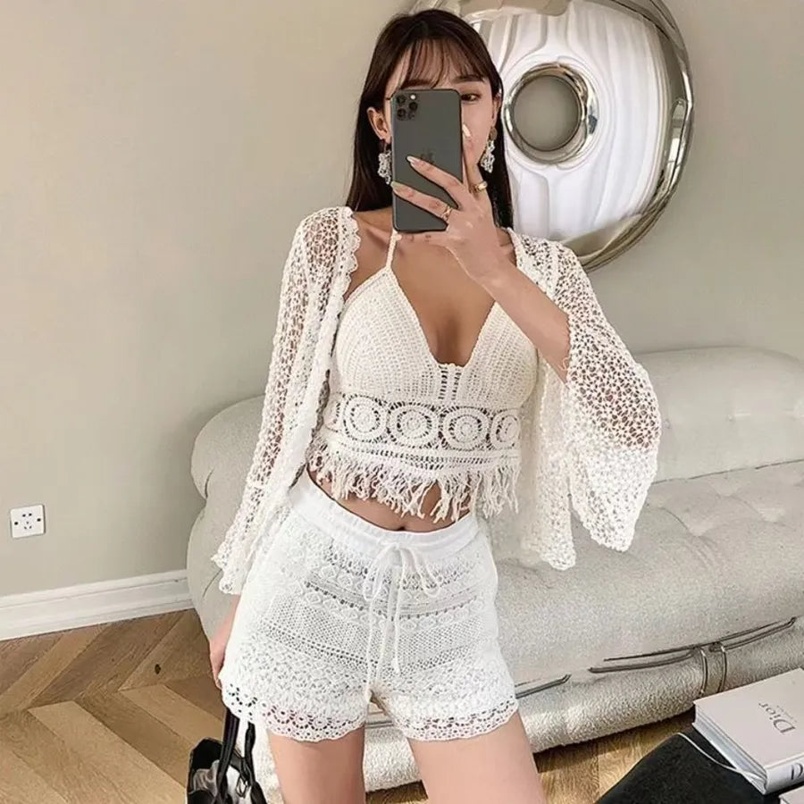 Woman taking a mirror selfie wearing a white lace outfit in a room.