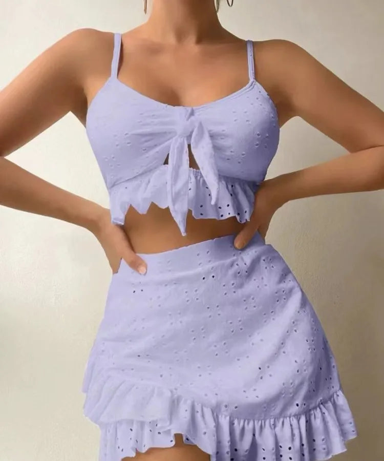 Person wearing a light purple two-piece outfit with a matching top and skirt on a plain background.