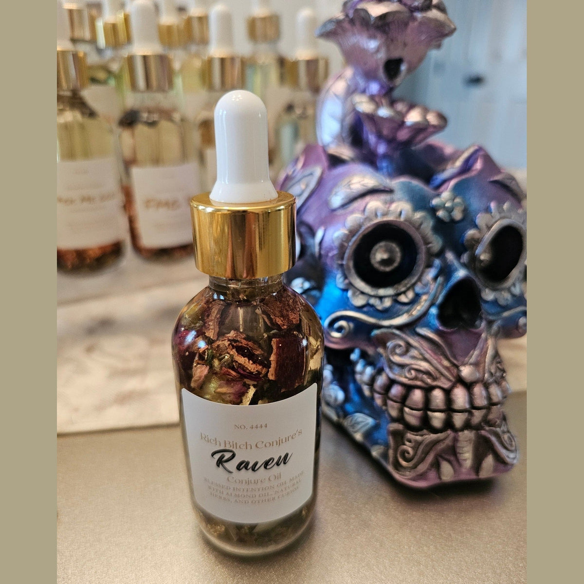 Bottle of 'Raven' with a dropper labeled 'Richland Company' next to a decorative skull. Raven Hoodoo Conjure Oil for Intuition, Manifestation, & Spiritual Power Ritual Oil