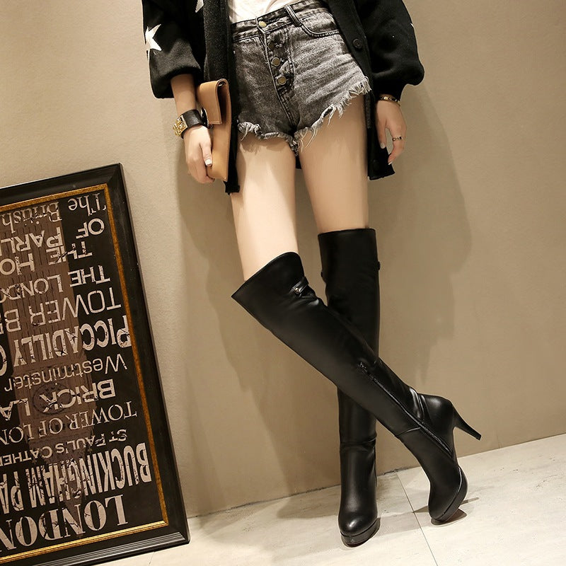 Person wearing black knee-high boots in a casual setting with a framed text piece on the wall.