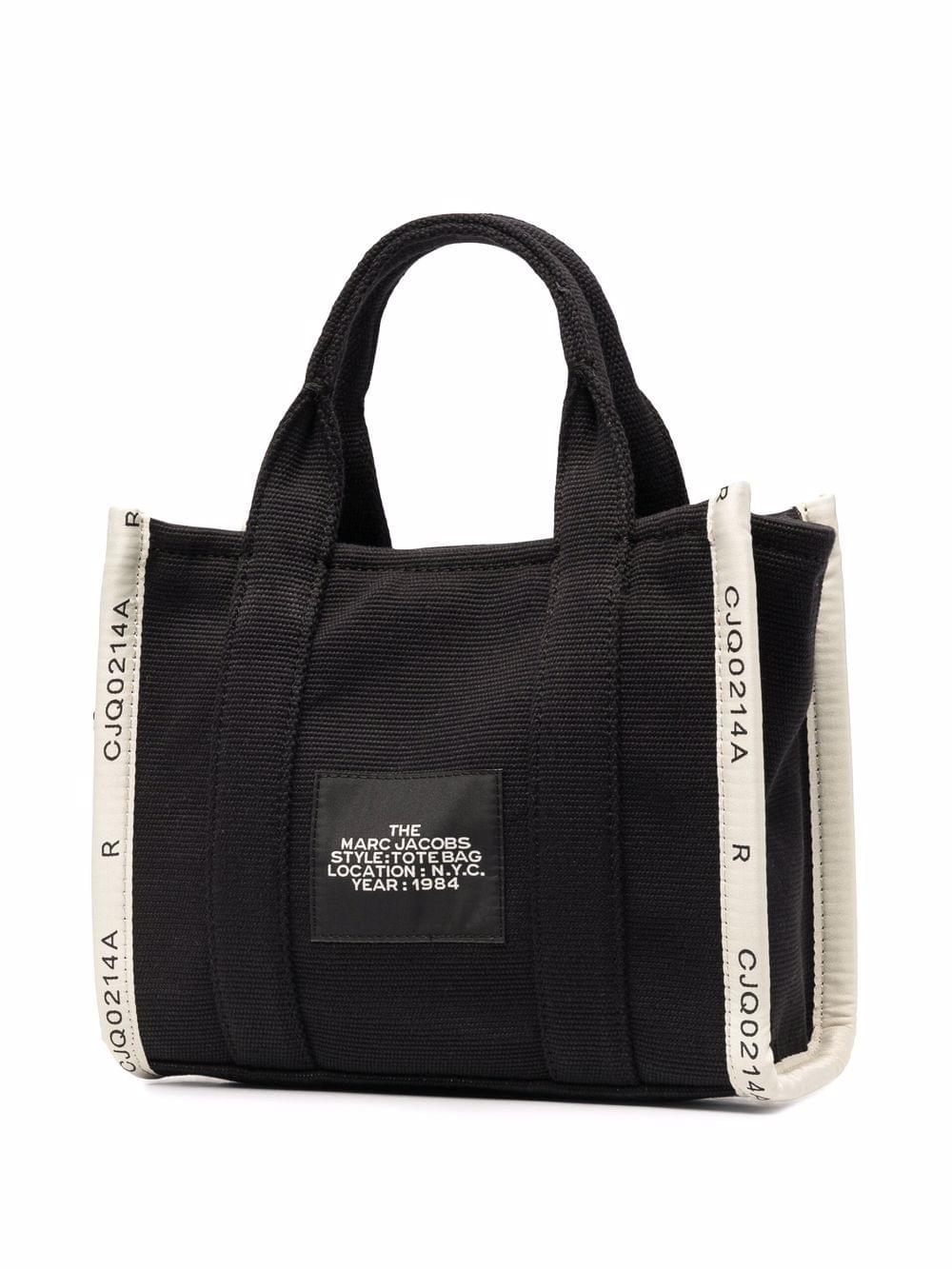 Black tote bag with white accents and brand label on a white background