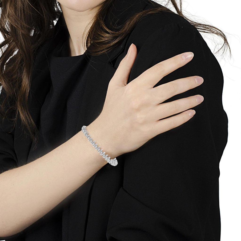 Person wearing a gold bracelet on a black background. 
