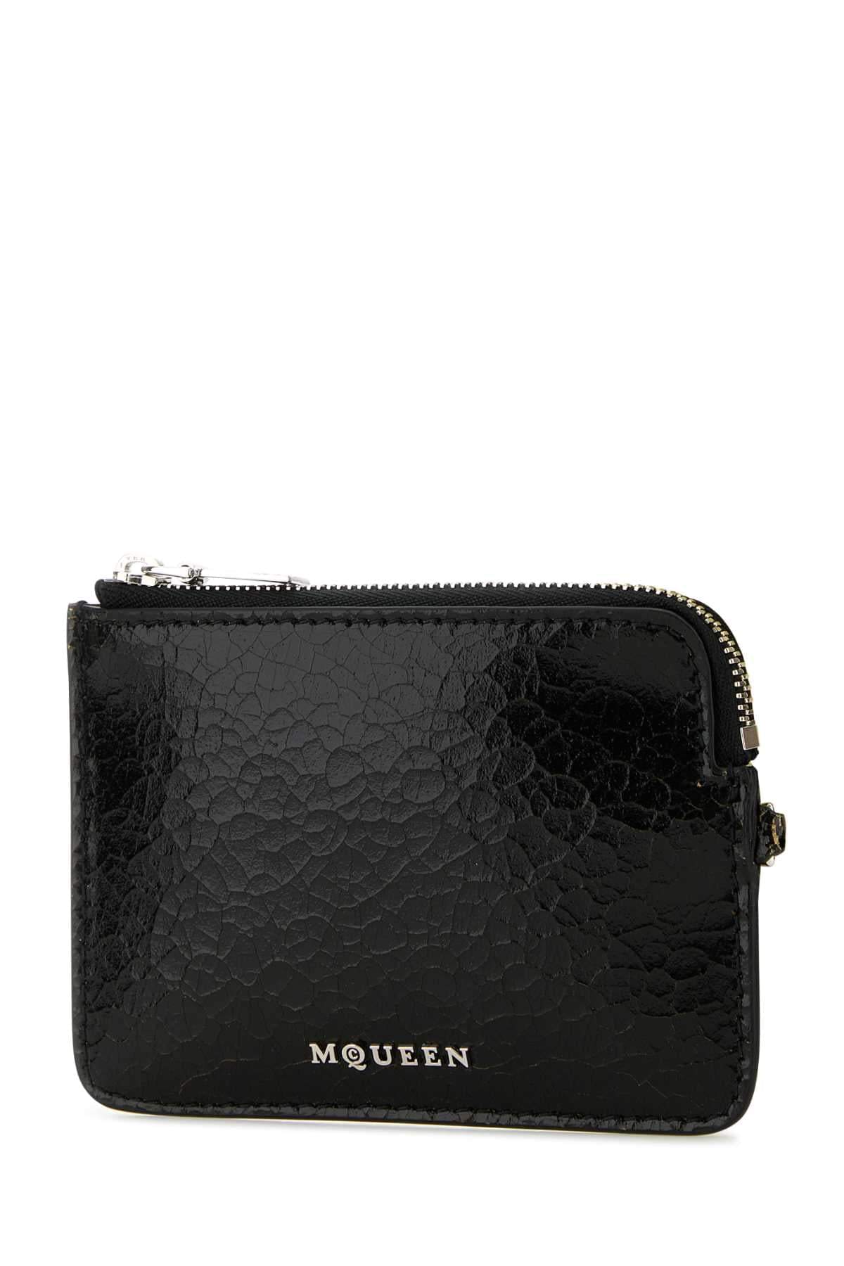 A black textured leather zip-around card holder pouch with silver-tone hardware and the brand name 'MQUEEN' printed in silver on the front, set against a plain white background.