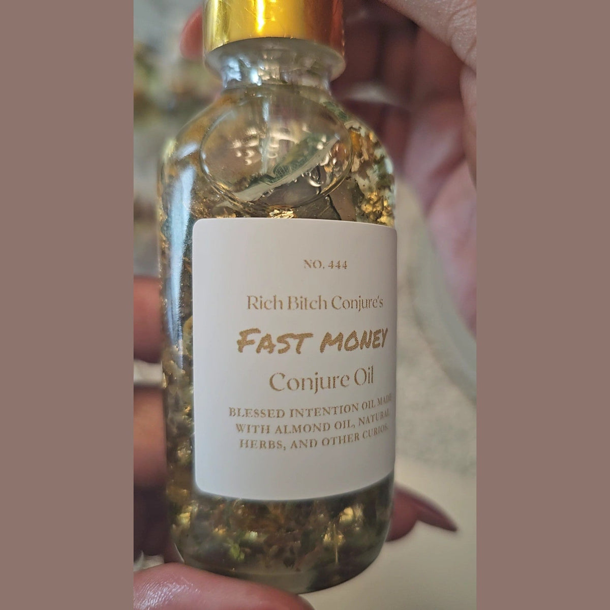 Bottle of 'Fast Money Conjure Oil' with a label held by a hand.