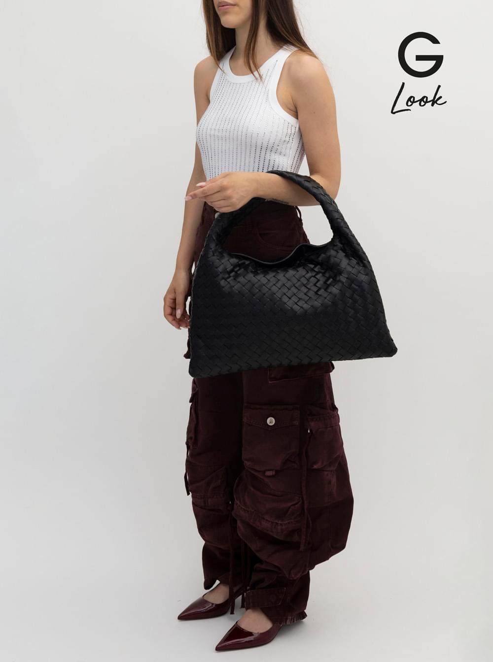 Person holding a black textured handbag against a white background