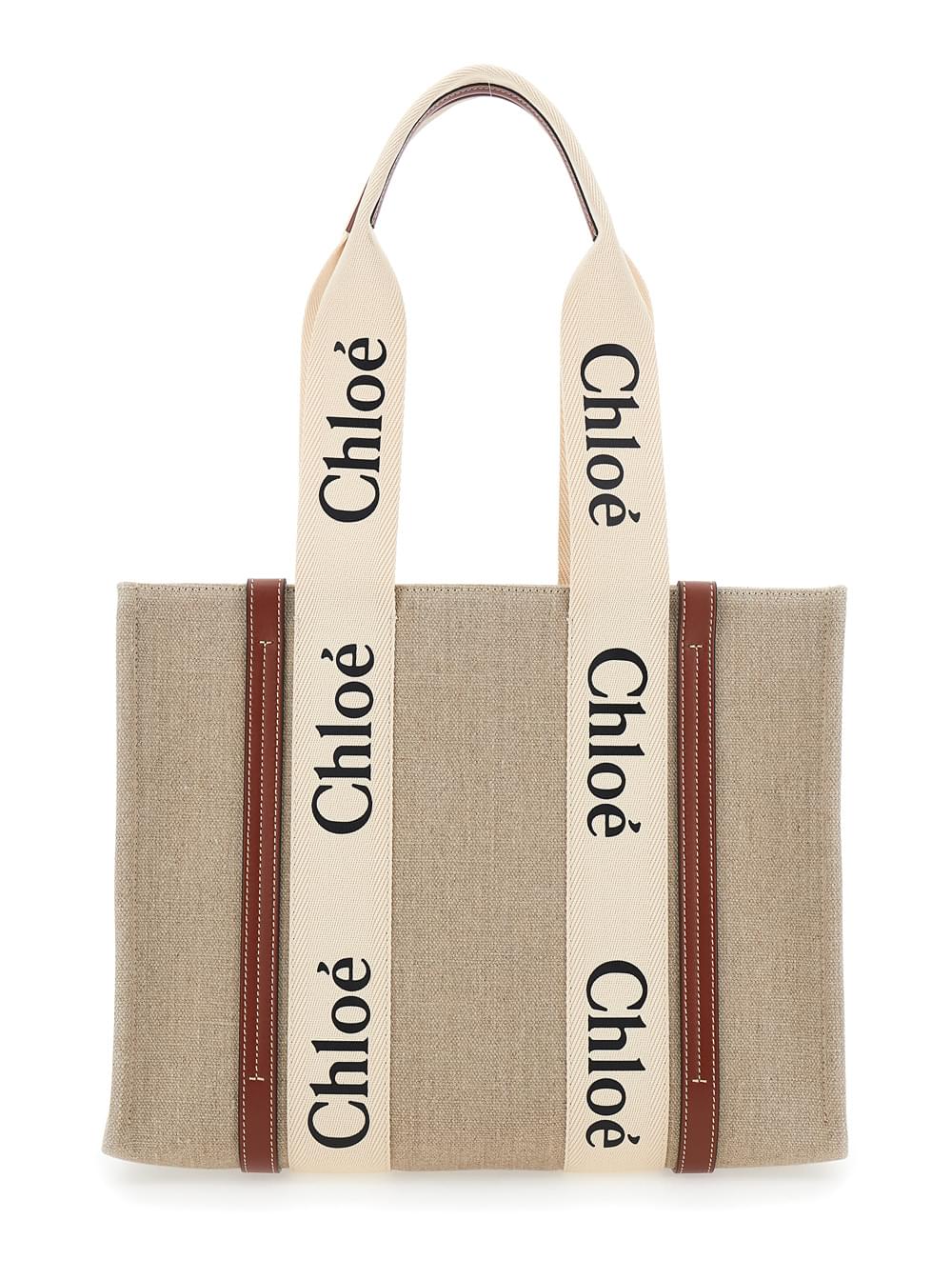 Chloé Woody medium tote bag in beige linen featuring brown leather trim and prominent logo lettering, captured against a clean white background.