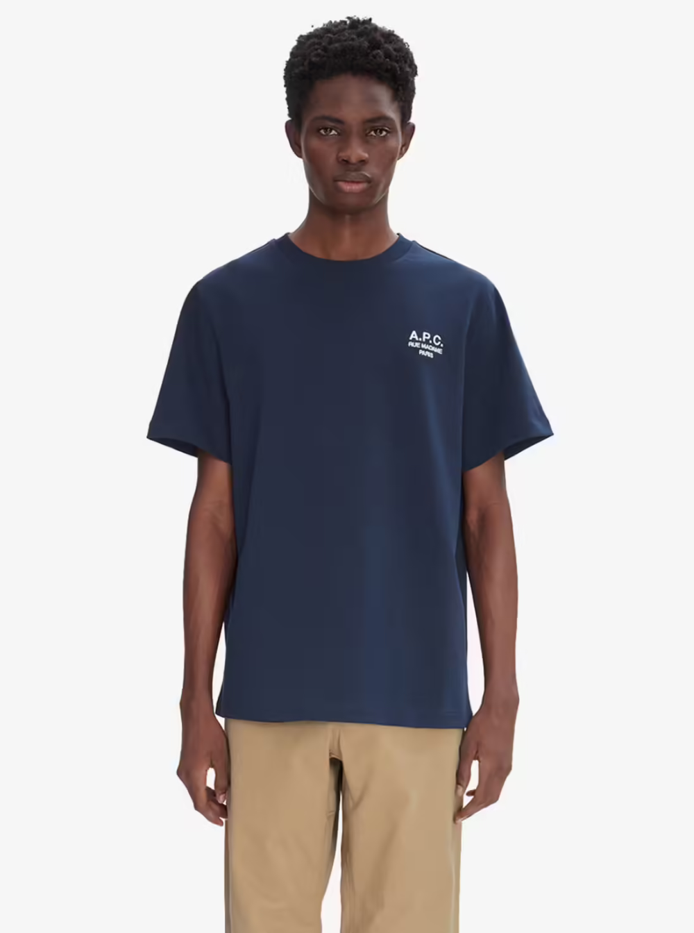 Model wearing a navy blue A.P.C. crew neck t-shirt with a white embroidered logo, captured against a clean white studio background.