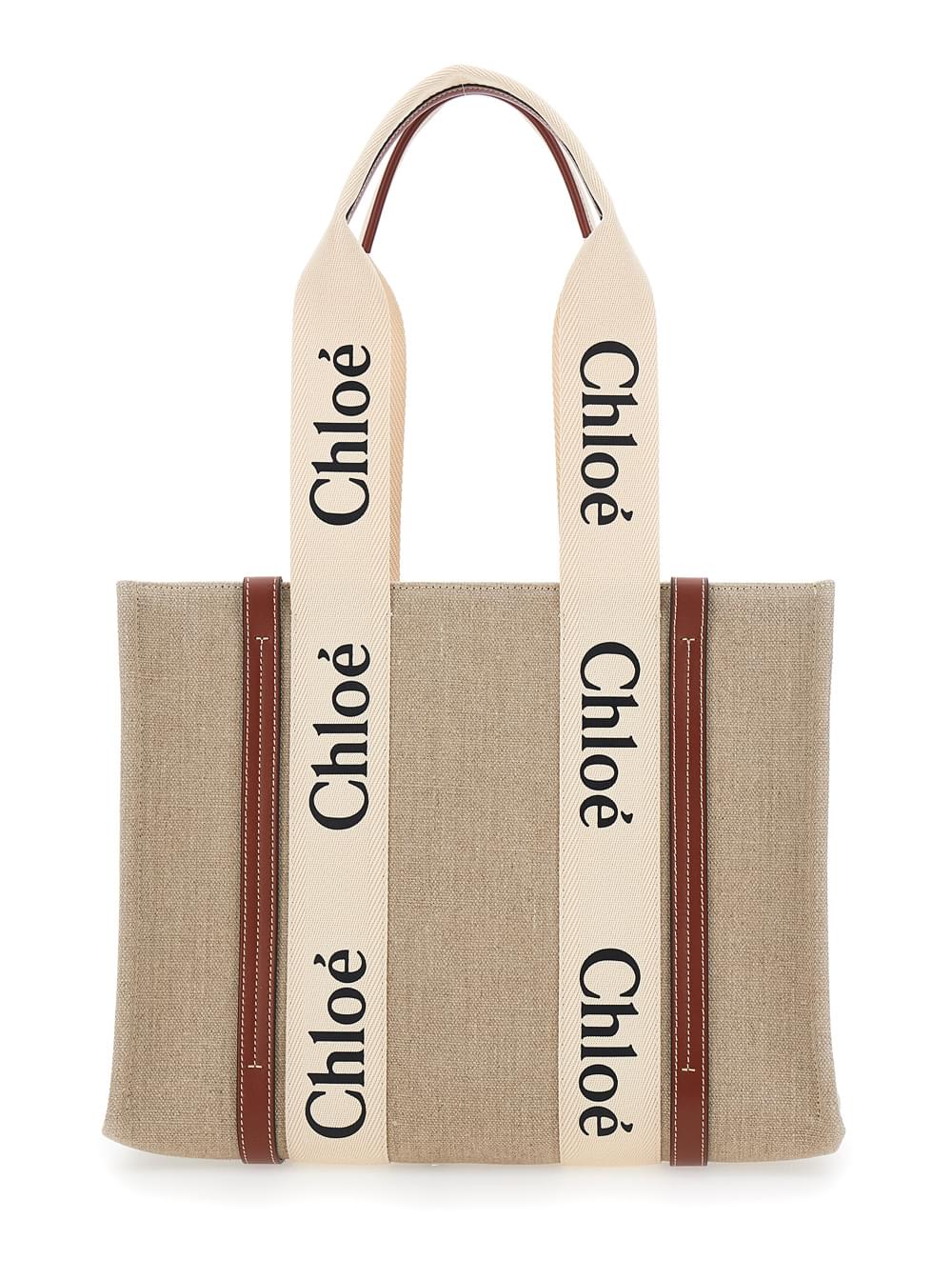 Chloé Woody medium tote bag in beige linen featuring signature logo lettering and brown leather trim, displayed against a clean white background.