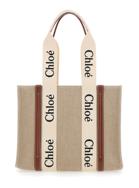 Chloé Woody medium tote bag in beige linen featuring signature logo lettering and brown leather trim, displayed against a clean white background.