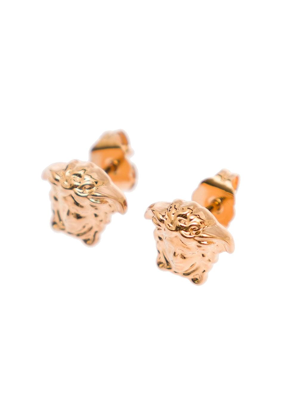 Versace Medusa Head earrings in gold brass featuring an embossed logo and butterfly clasp, displayed against a clean white background.