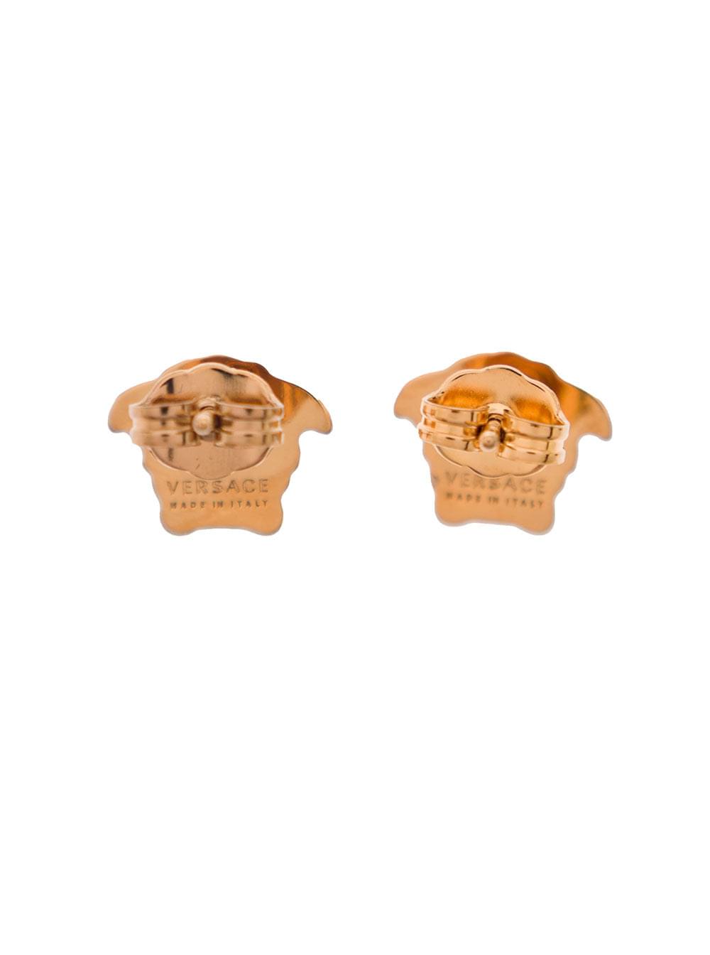 Versace Medusa Head earrings in gold brass featuring an embossed logo and butterfly clasp closure, isolated against a white background.