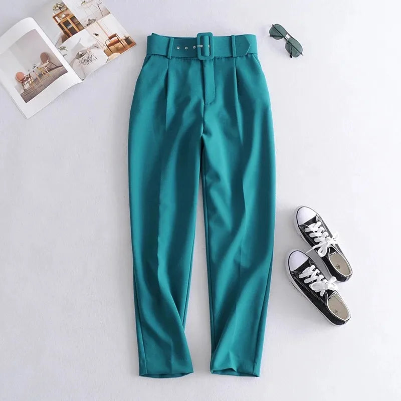 Teal pants with a belt, black sneakers, and sunglasses on a light gray background high waisted pants women, pleated trousers women, ankle length pants, slim fit trousers, business casual pants, work pants women, office trousers, women's dress pants, casual chic outfit, tailored pants women, everyday trousers, spring fashion women, autumn pants women, elegant trousers, commuter style fashion, women's workwear, high rise pants, fashion trousers women, travel pants women, versatile wardrobe essentials