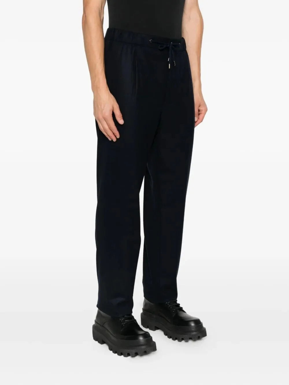 Person wearing black pants and black shoes on a white background