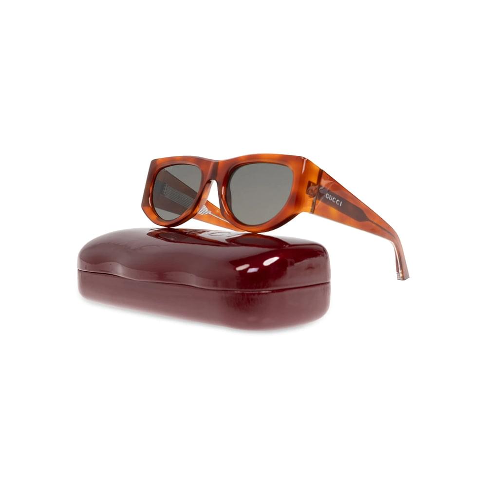 Sunglasses with tortoiseshell frame and dark lenses on a red case against a white background