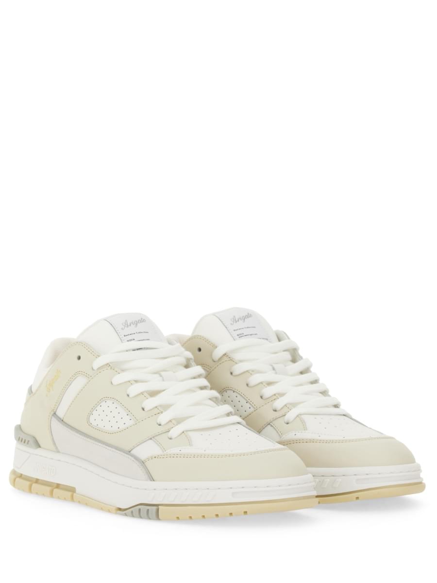 A pair of low-top sneakers in off-white and cream tones with white laces and a light beige sole, shown against a plain white background.