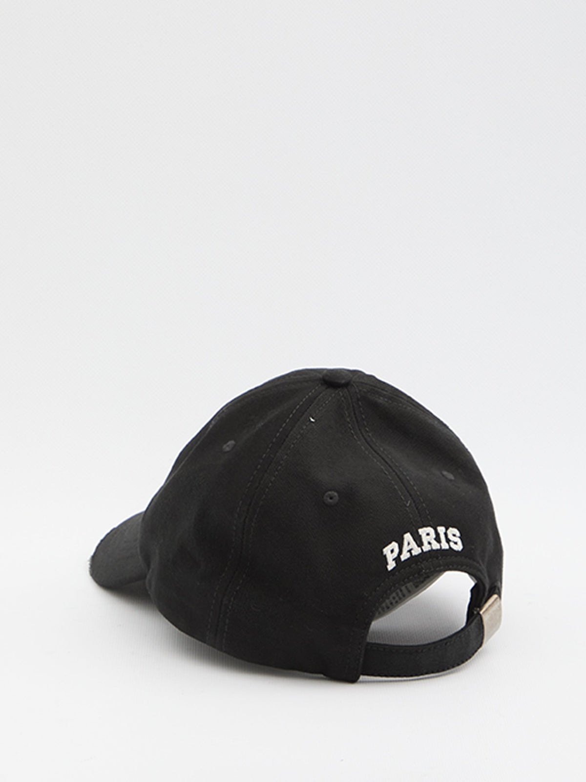 A black baseball cap shown from the back, featuring 'PARIS' embroidered in white on the side and an adjustable strap with a small gold-tone metal rivet.