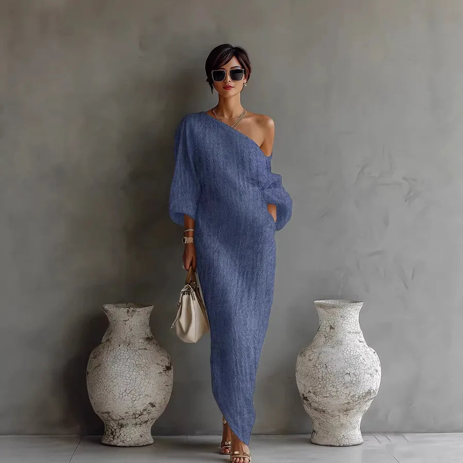 Woman in a blue dress standing between two vases against a gray wall