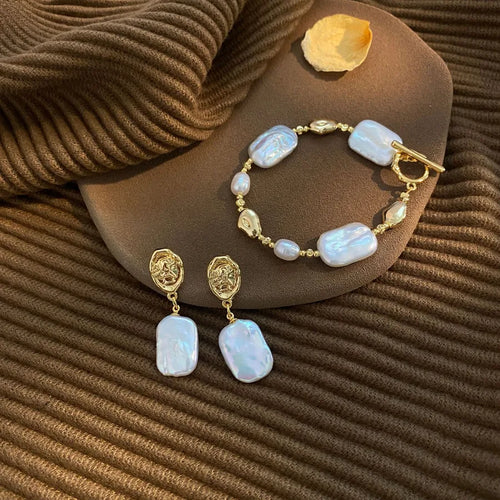 Pearl bracelet and earrings on a brown textured surface