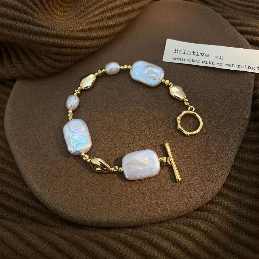 Pearl bracelet with gold accents on a brown textured surface