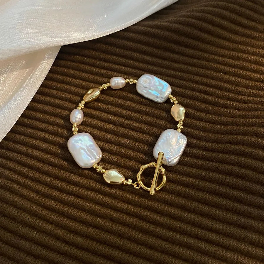 Pearl bracelet with gold accents on a brown textured surface