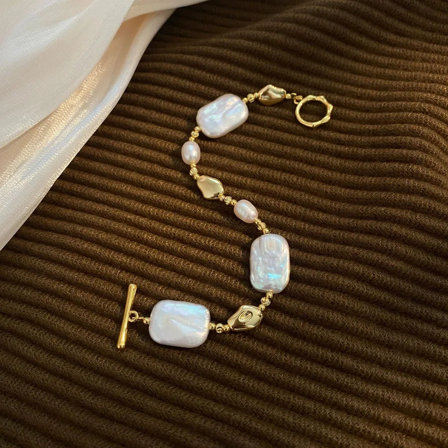 Gold bracelet with white pearls on a brown textured surface