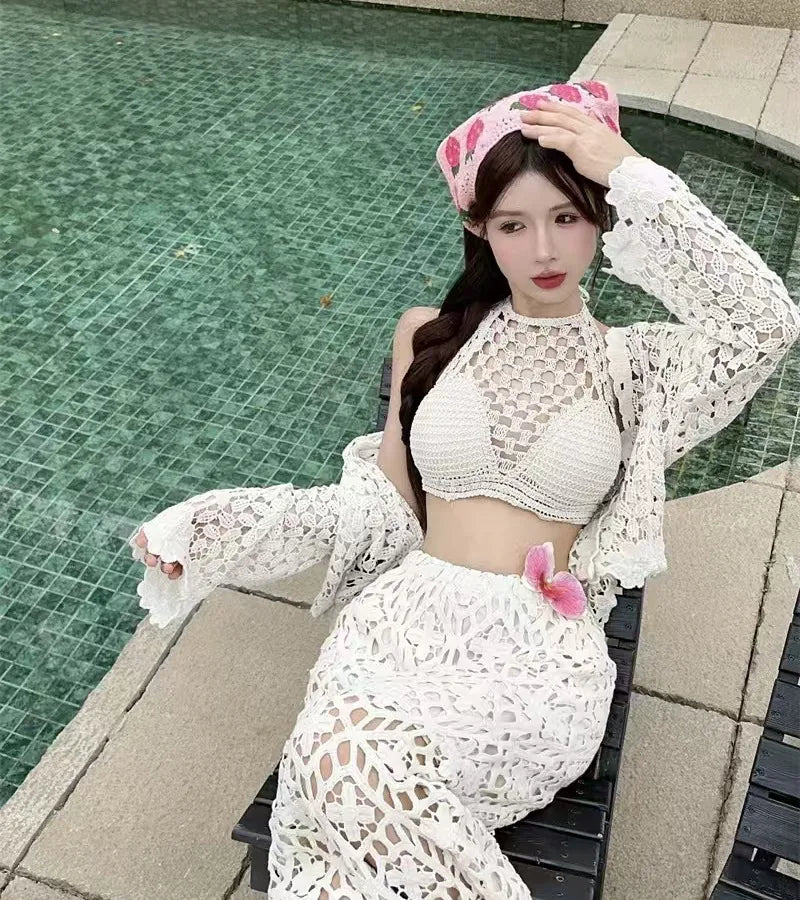 Woman in a white crochet outfit sitting by a pool