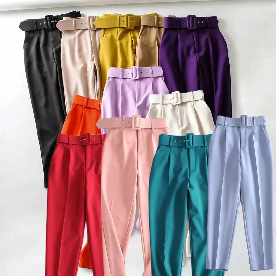 12 pairs of pants. A variety of solid color pants with belts displayed against a white background