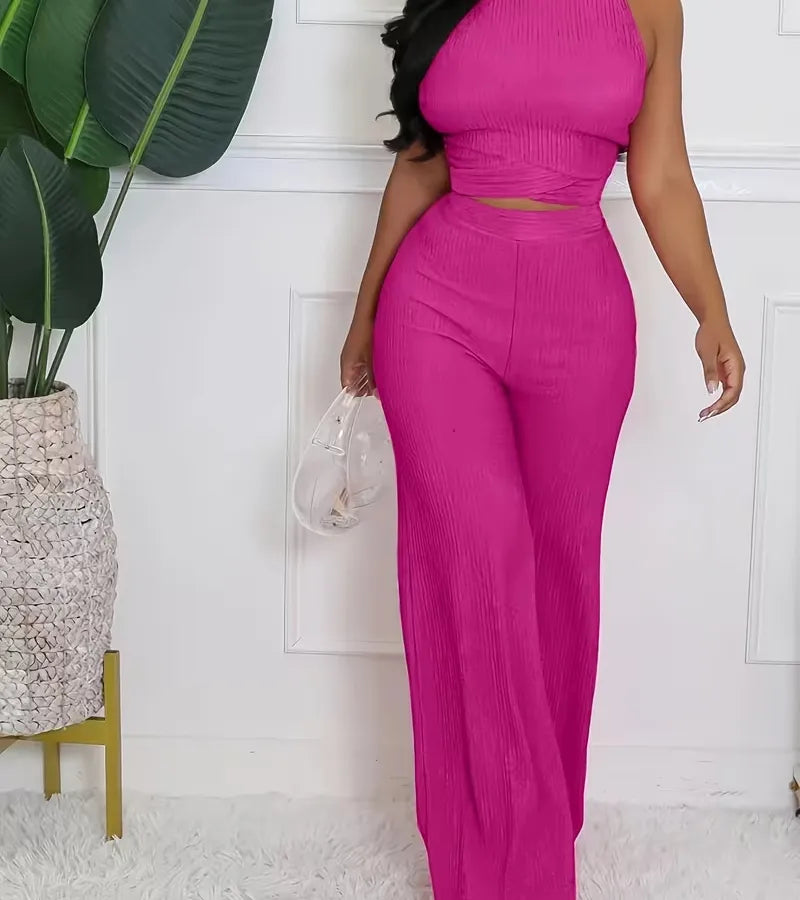 Person wearing a bright pink outfit standing in a room with a plant and white wall.