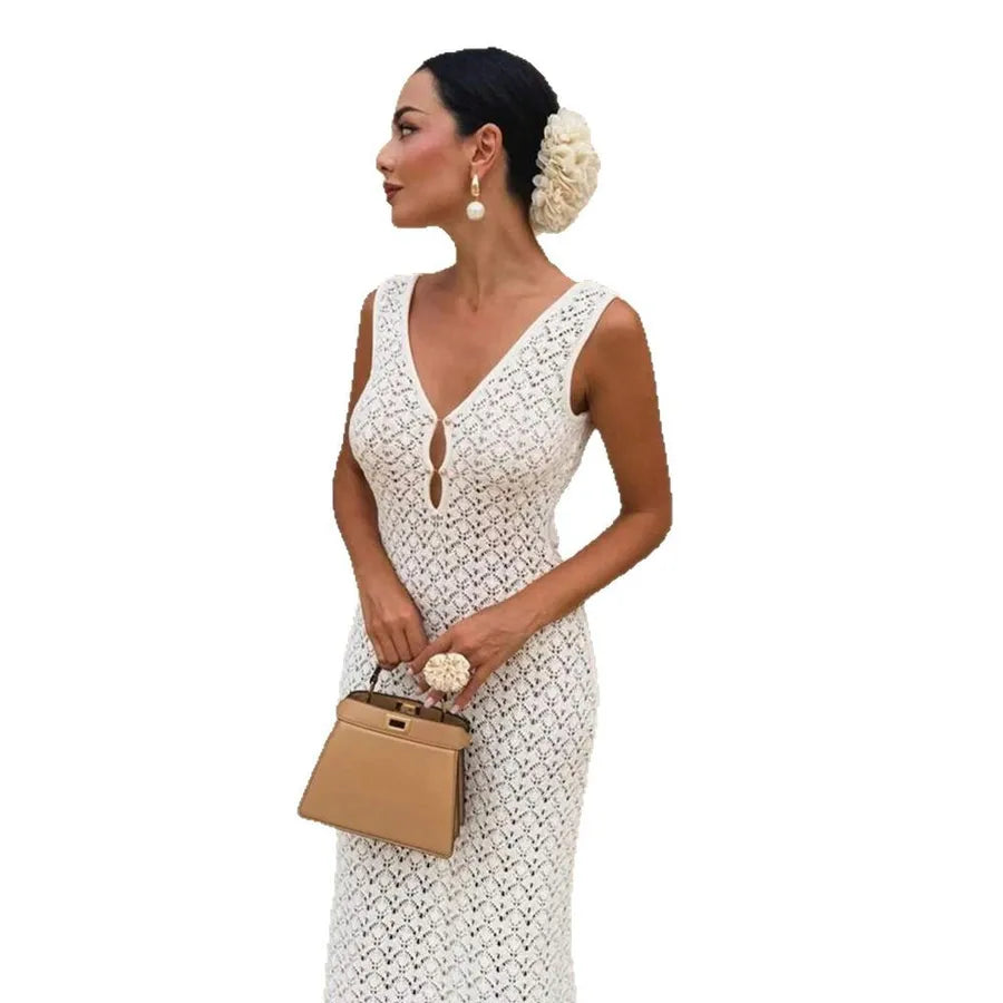 Woman in a cream colored white lace dress holding a beige handbag on a white background