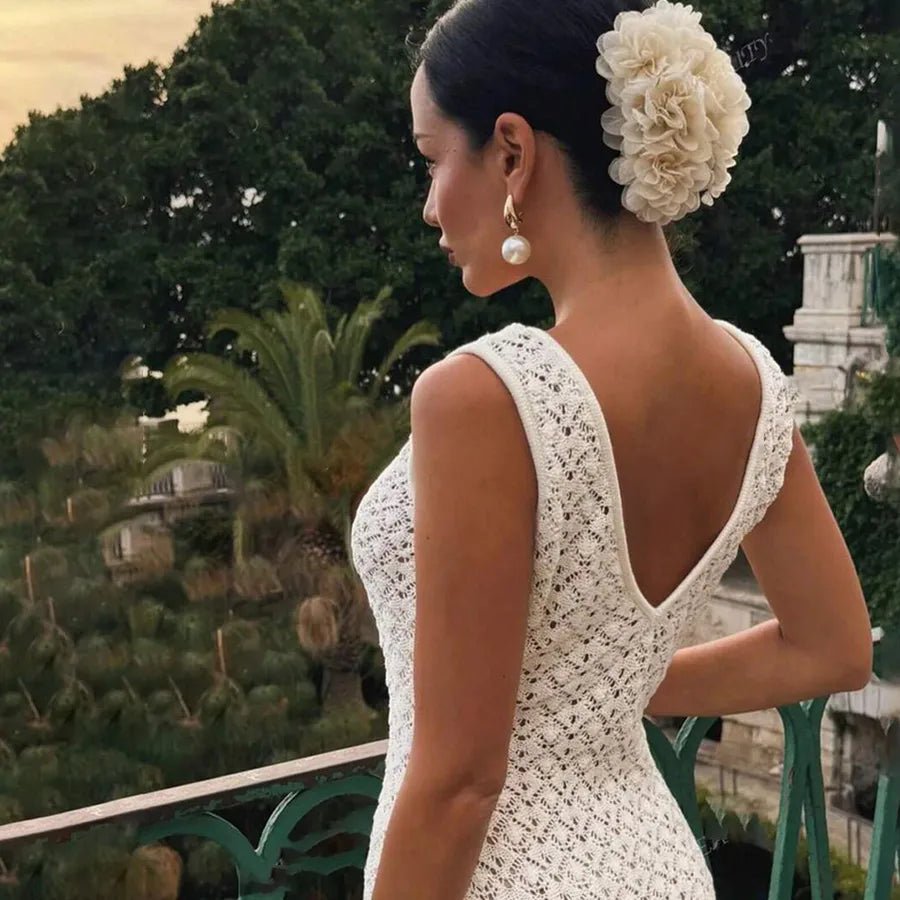 Woman in a cream colored lace dress with a floral headpiece in an outdoor setting