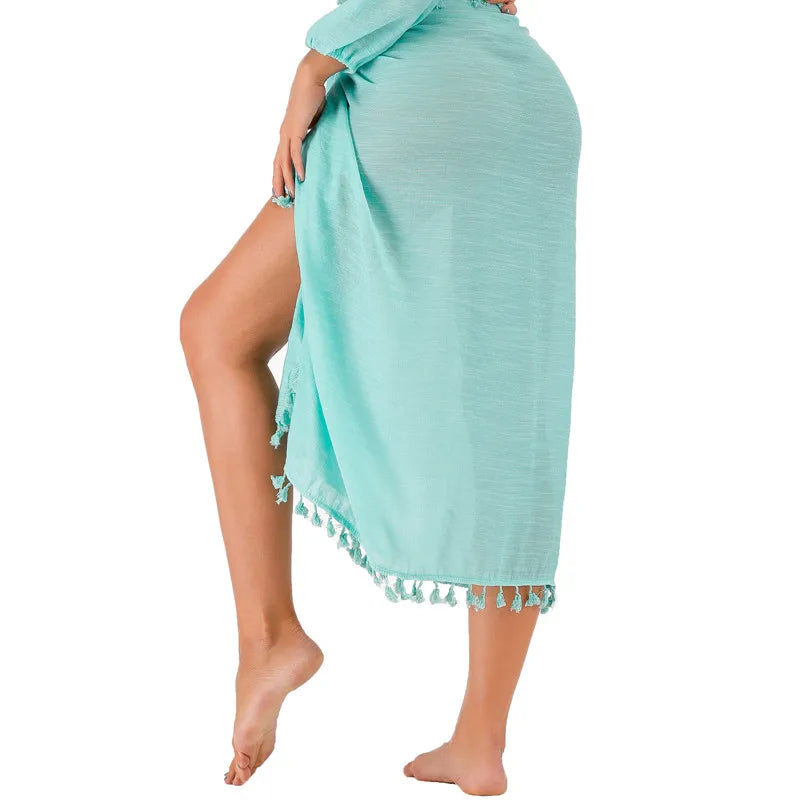 Turquoise towel with tassels draped over a person on a white background