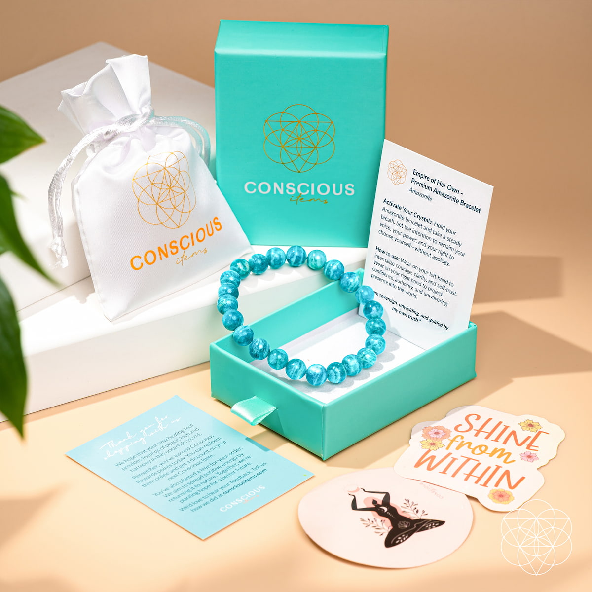 Turquoise beaded bracelet in a box with 'Conscious' branding, including a card and coaster on a wooden surface.Empire of Her Own – Premium Blue Amazonite Bracelet
