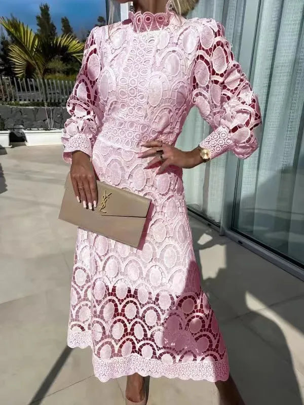 Woman wearing a pink lace dress holding a beige clutch outdoors.