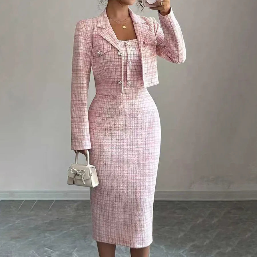 Person wearing a pink checkered suit holding a white handbag against a plain background