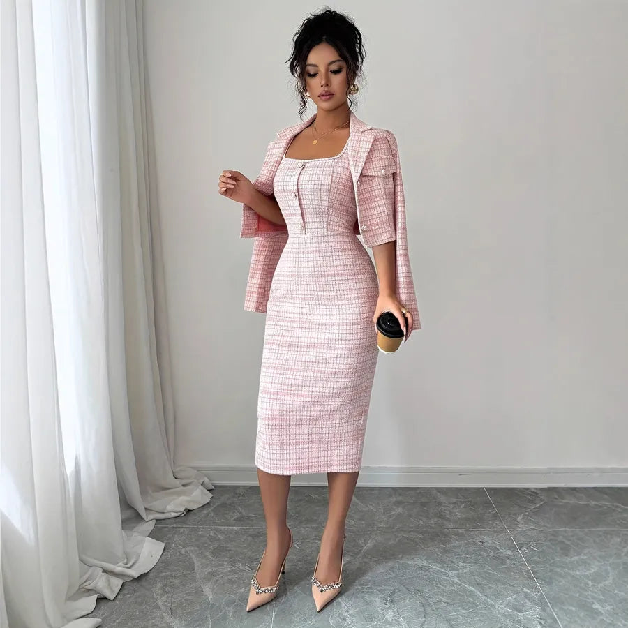 Woman wearing a pink checkered dress with a matching jacket against a white curtain background