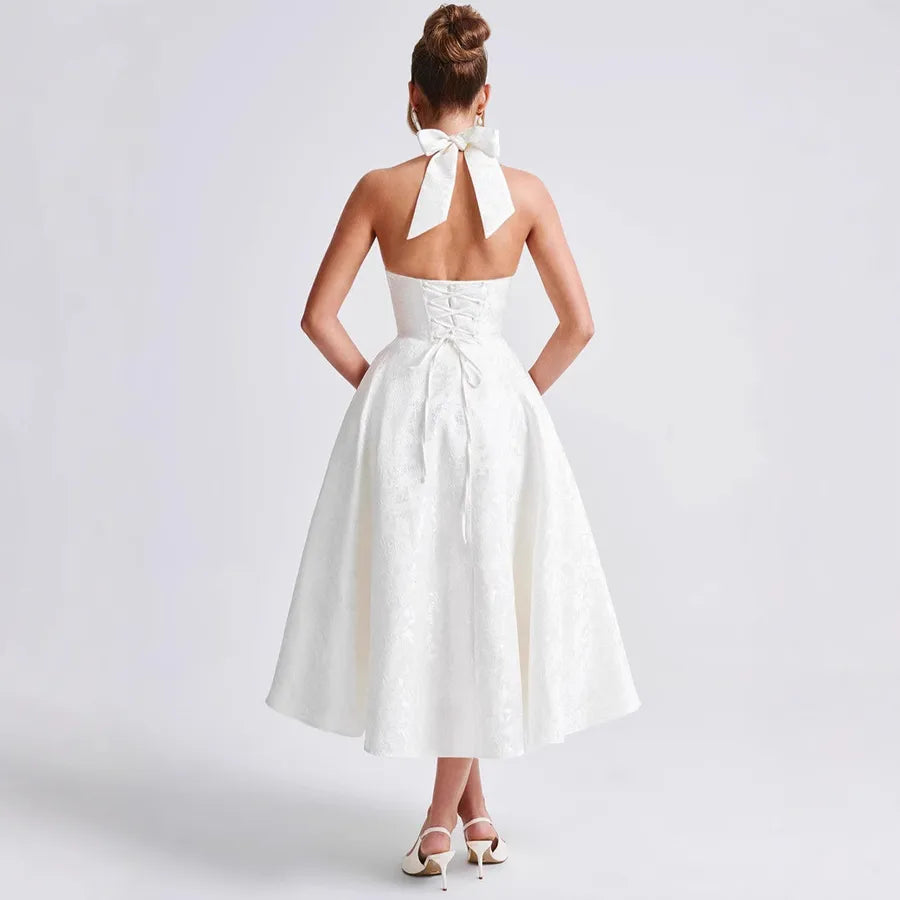 White dress with a bow detail on the back worn by a person against a plain background