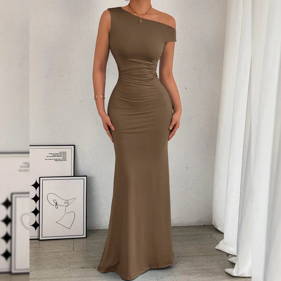 Woman wearing a brown off-shoulder dress in a minimalistic room with white walls and curtains.