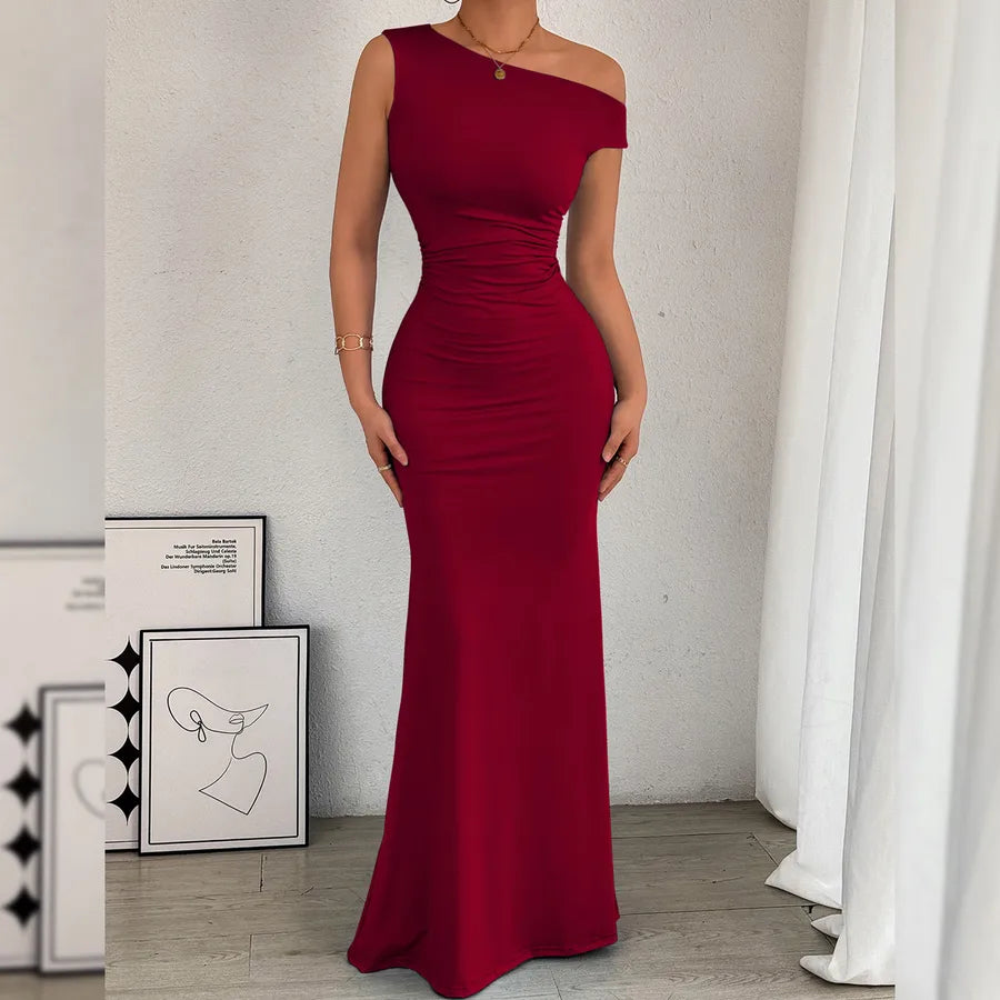 Red evening gown worn by a person in a minimalistic room with white walls and curtains.