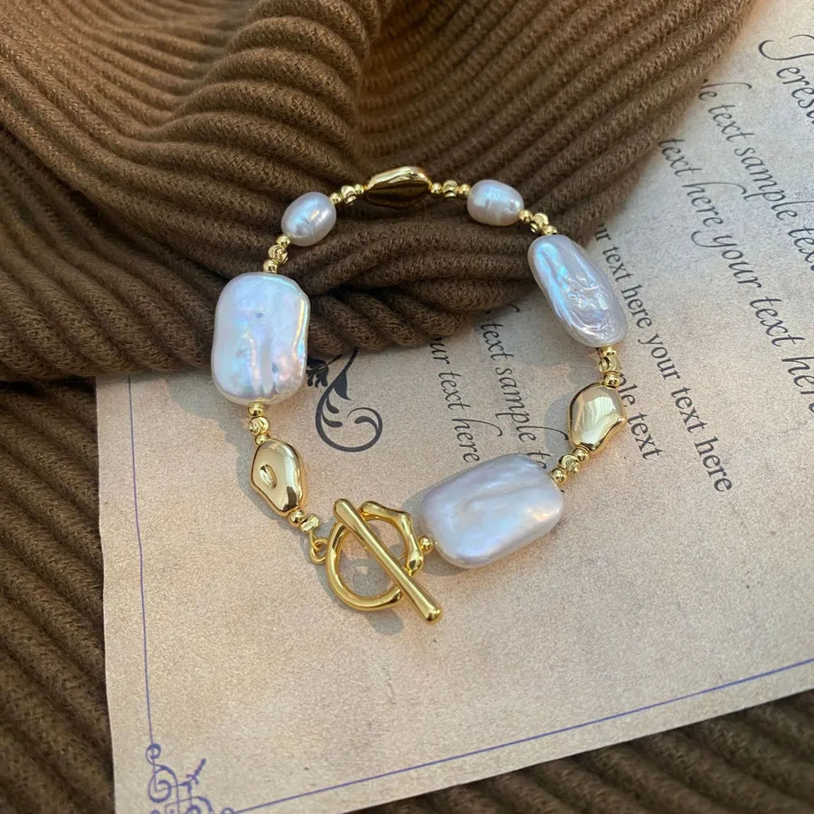 Pearl bracelet with gold accents on a textured surface