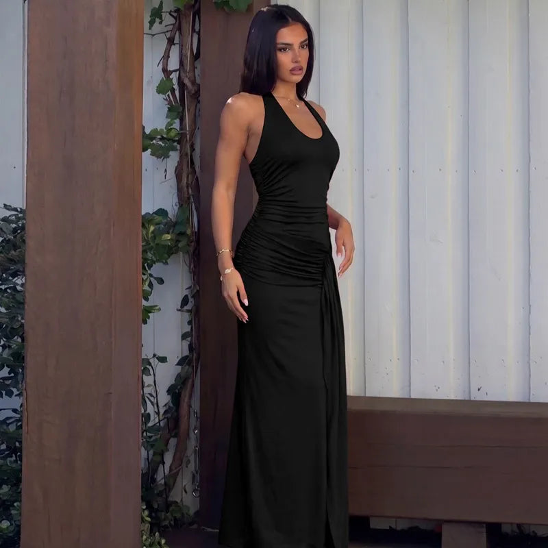 Woman in a black dress standing against a wooden and white wall.