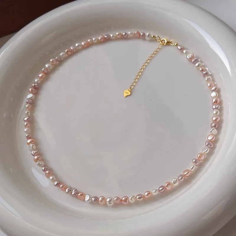 Pearl necklace with a gold clasp on a white plate