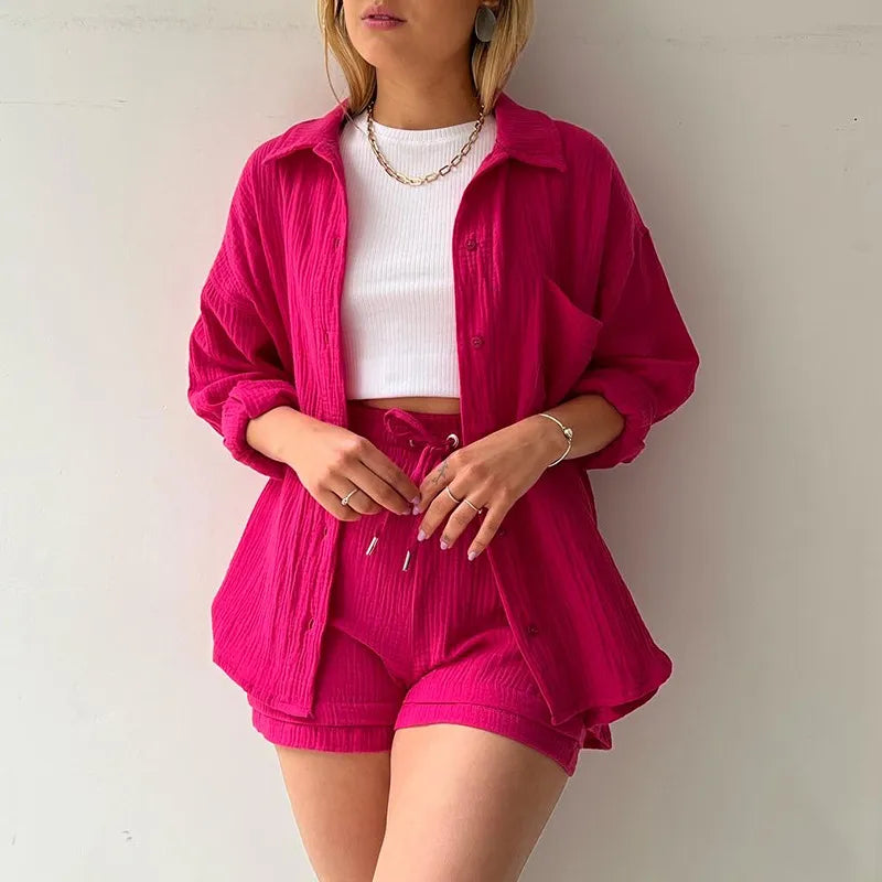 Person wearing a bright pink outfit with a matching jacket and drawstring shorts on a plain background.