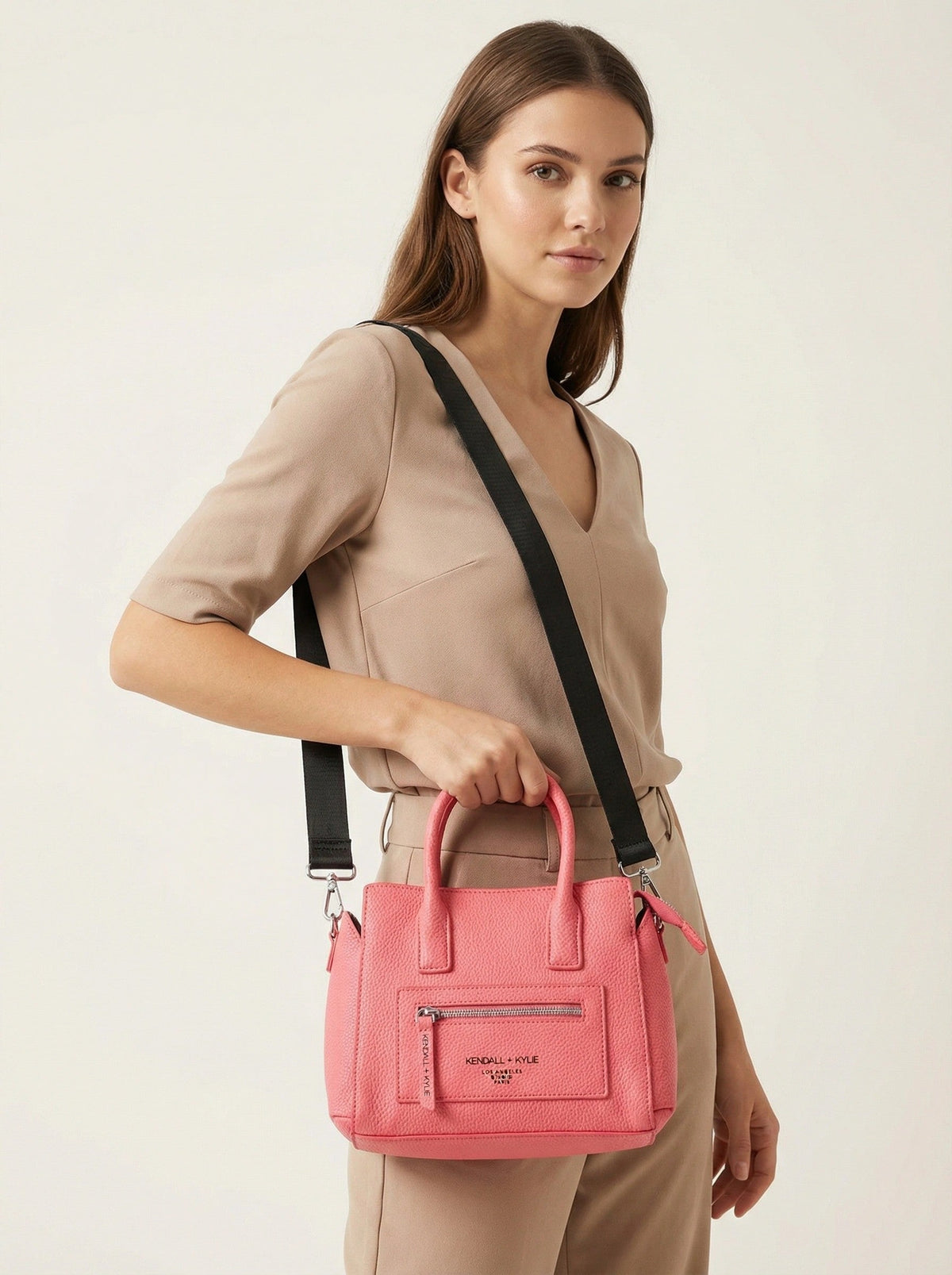 Woman holding a pink handbag with a beige background